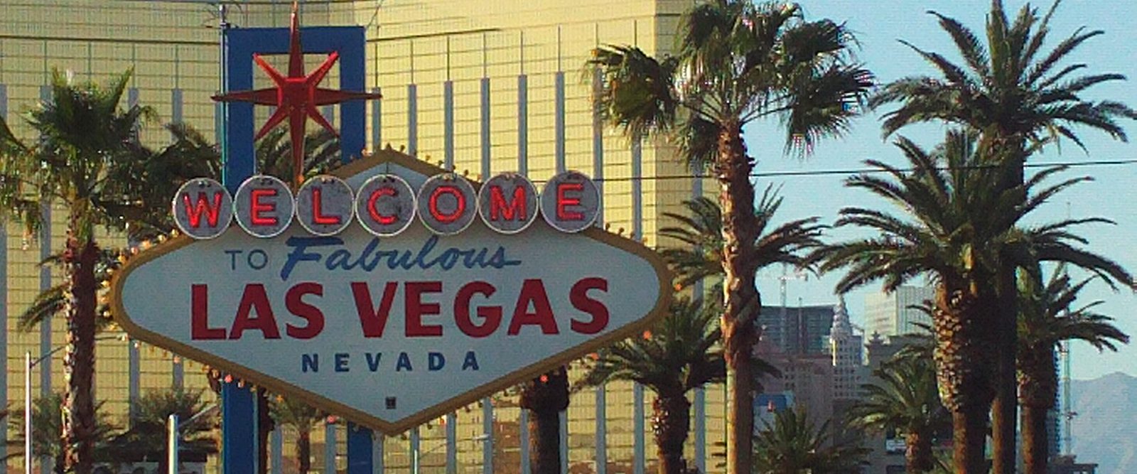 The Welcome to Fabulous Las Vegas sign surrounded by palm trees in warm late-afternoon light
